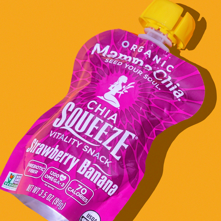 Pink pouch of Mamma Chia Squeeze Strawberry Banana snack on orange background. USDA organic, 70 calories, high in Omega-3 and prebiotic fiber. Playful vibe.